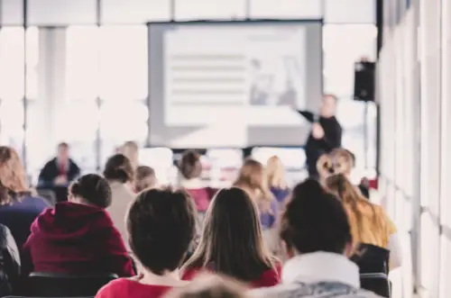 Man giving a lecture and/or teaching on a projector board to a brightly lit room full of adults. New Jersey Crash reconstructionist Accident investigator Accident investigations Accident expert Fleet consultant Fleet consulting Trucking Safety consulting Driver safety training